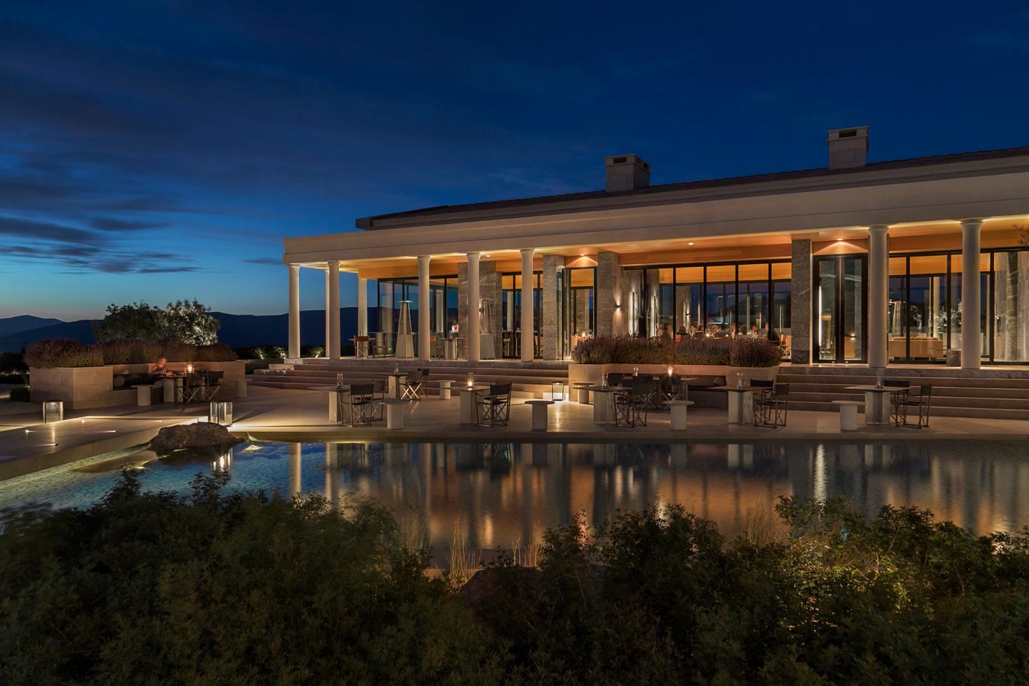 Amanzoe's colonnaded pavilion lit at dusk over the reflection pool
