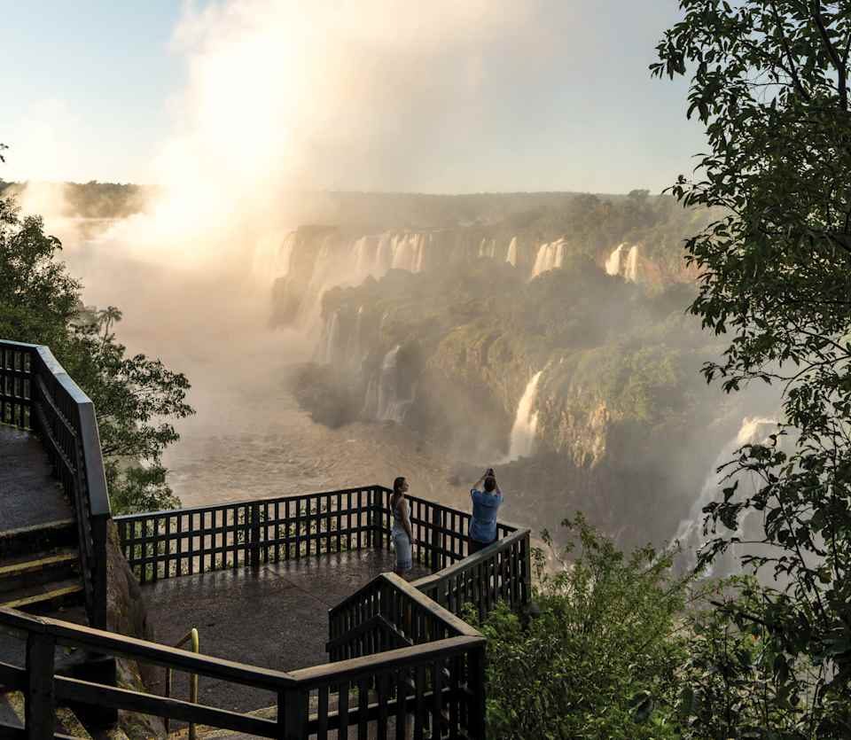 Couple photographing Iguassu Falls at sunrise