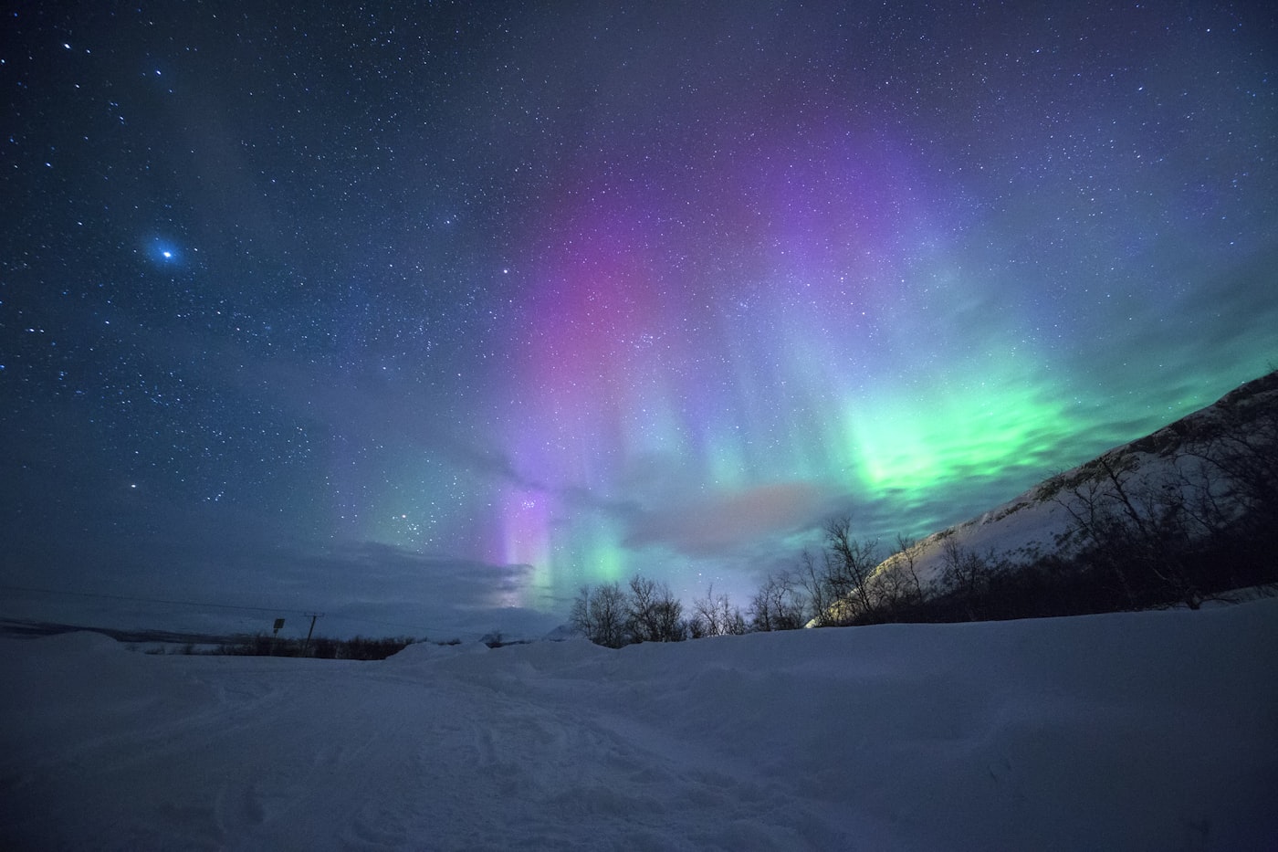 Aurora borealis over a snow-covered landscape in the high Arctic