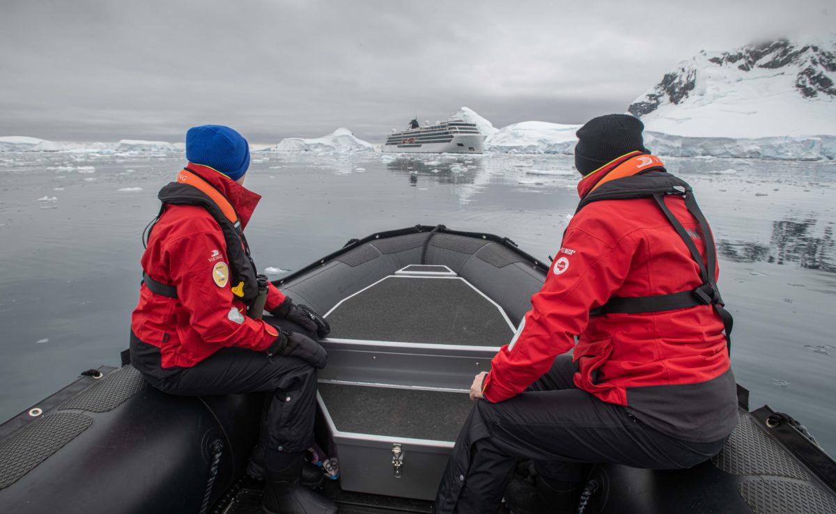 Two guests in Viking expedition parkas return to Viking Octantis by zodiac in Antarctic waters
