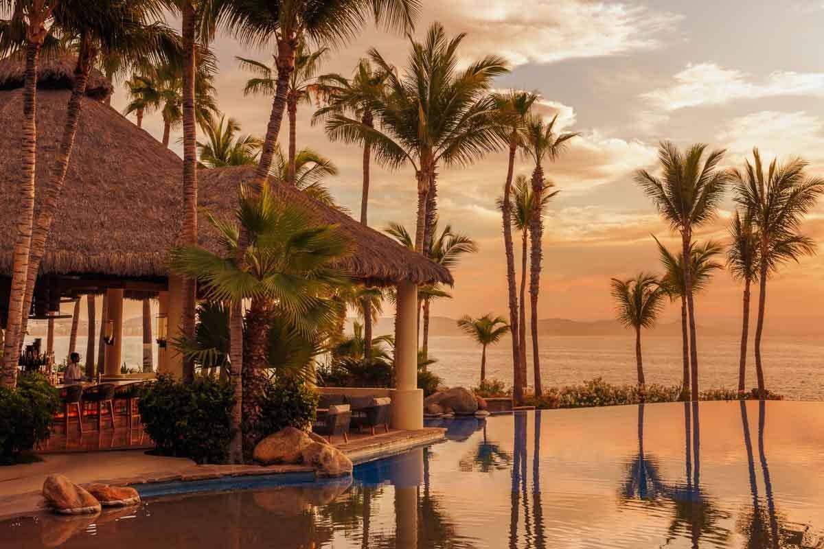 One&Only Palmilla infinity pool and thatched palapa at sunset over the Sea of Cortez