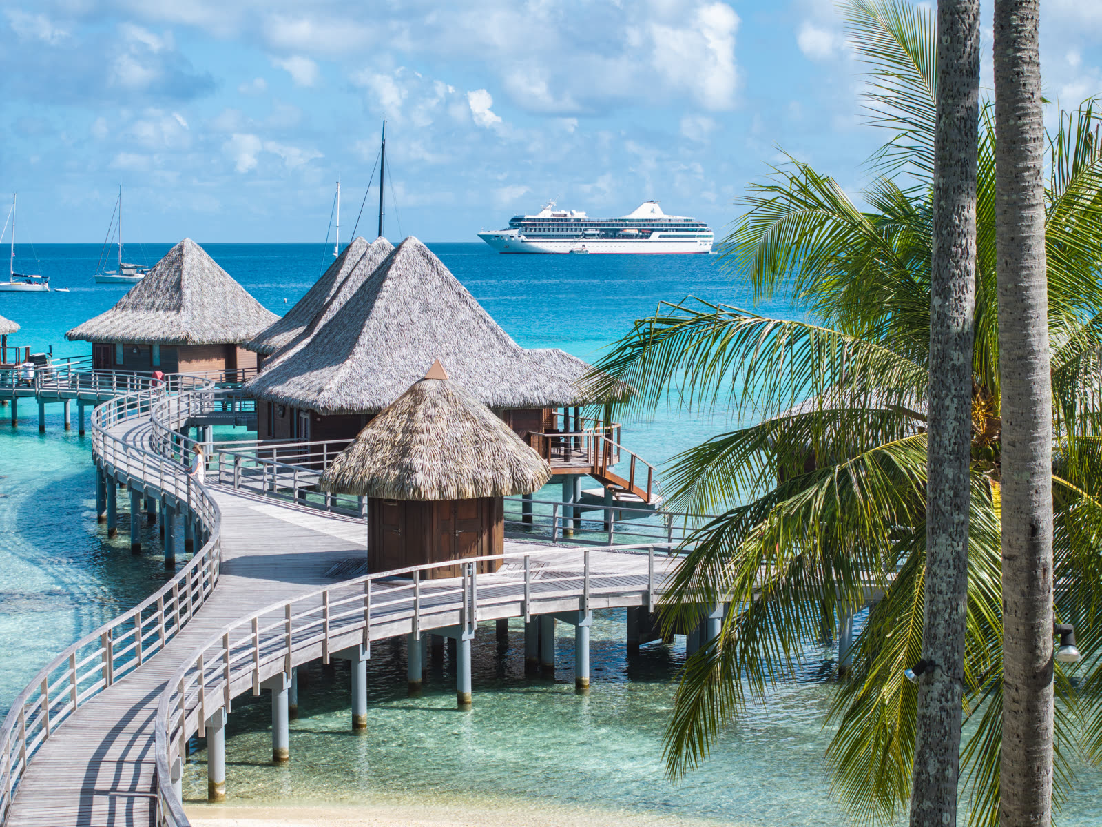 Overwater bungalows and the m/s Paul Gauguin in a Polynesian lagoon